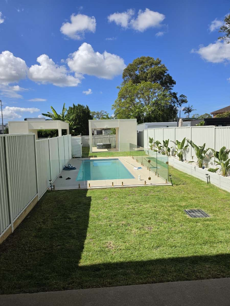 Backyard lawn around a glass-fenced pool